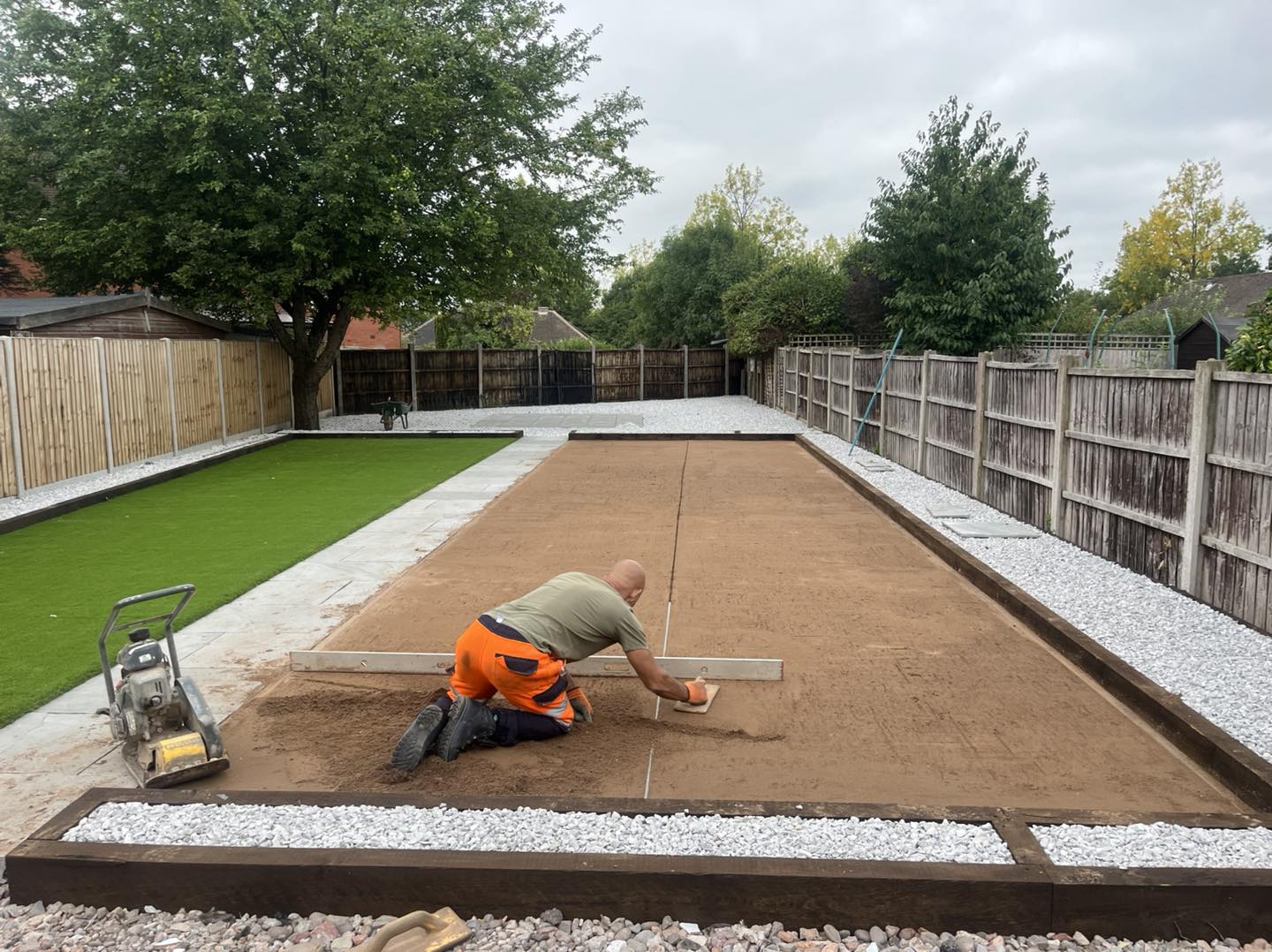 Worker smoothing out garden surface in preparation for new turf being laid in Solihul